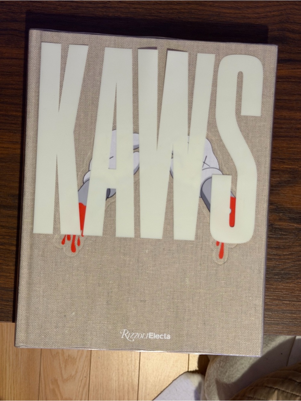 KAWS Beige Cover Art Book with White Lettering and Red Accents
